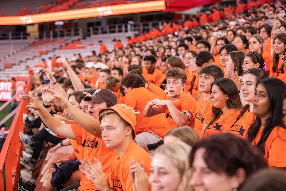 Students cheering together in the JMA Wireless Dome wearing orange.